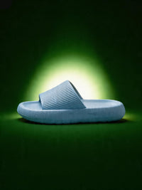 Light blue slide sandals on a dark green background